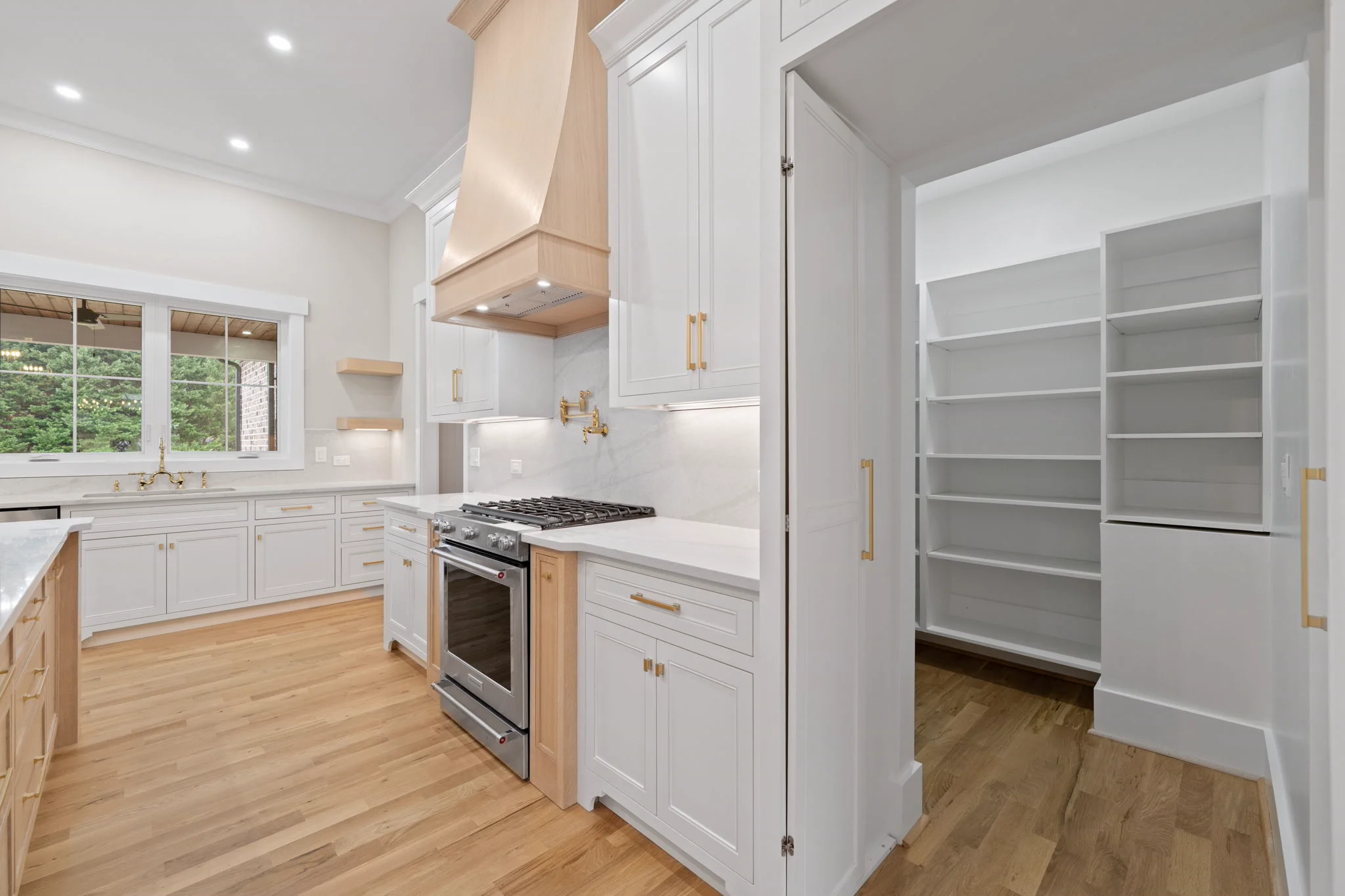 Custom white oak kitchen island with hidden outlets, matching sliding hood, and inset butler’s pantry by Borough Woodworks