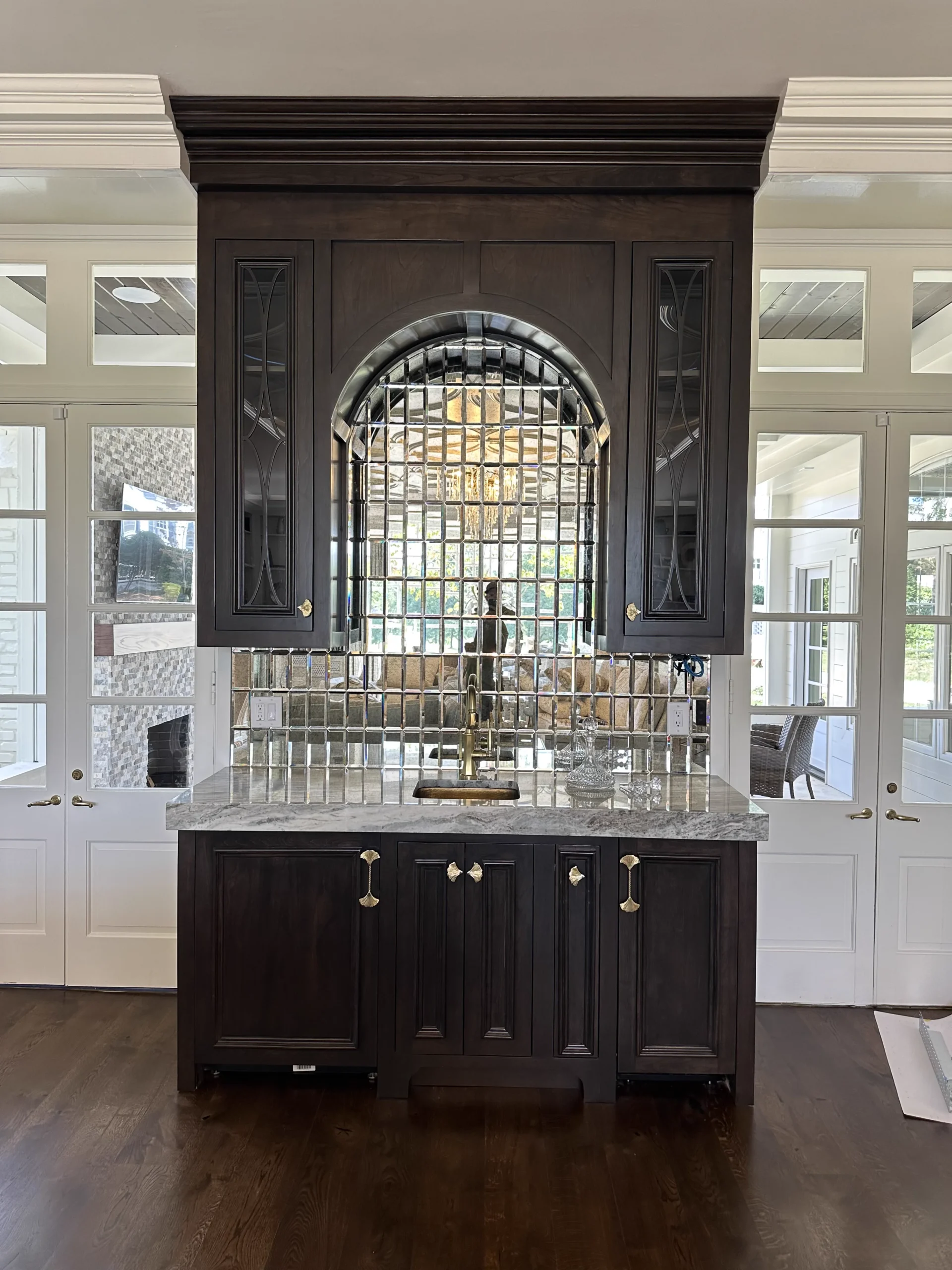 Custom stained cherry wet bar with built-in appliances, featuring glass cabinet doors with a solid cherry CNC-machined mullion and mirrored tile backsplash.