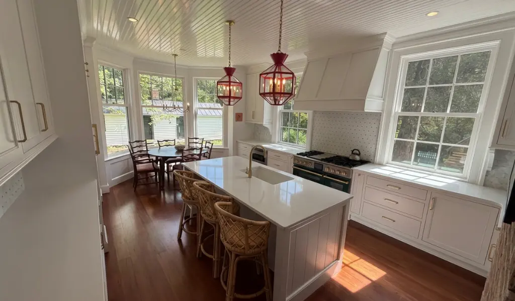 Custom white kitchen with organized cabinetry, large island, custom range hood, and built-in storage