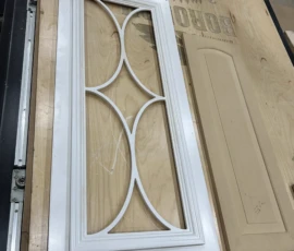Custom cabinet door featuring a decorative mullion insert displayed beside a raised panel cabinet door, showcasing custom door styles manufactured by Borough Wood Works.