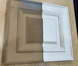 Close-up of a custom cabinet door corner profile showing unfinished and primed raised panel details with precision CNC craftsmanship.
